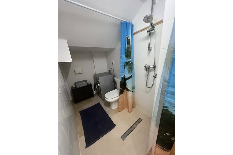 Badezimmer mit ebenerdiger Dusche und Waschmaschine