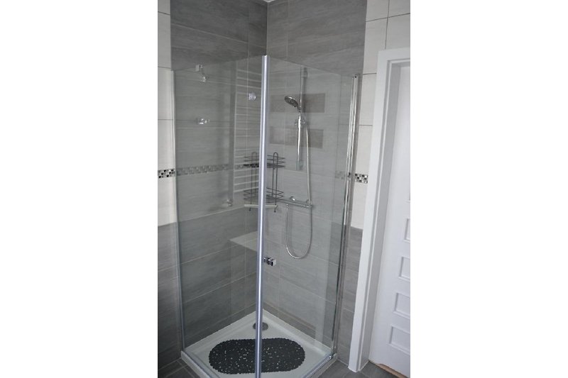 Moderne Badezimmer mit transparenter Duschtür und stilvollem Griff. Handtuchheizung und Föhn vorhanden