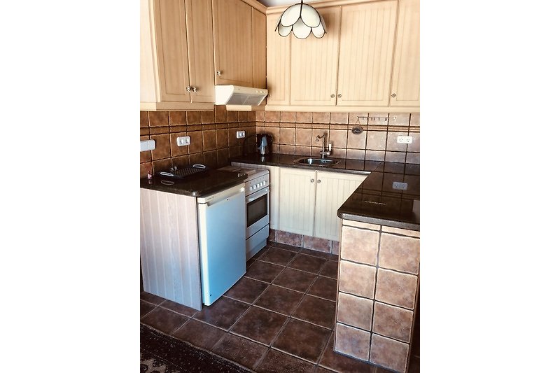 Gemütliche Küche mit braunen Schränken, Arbeitsplatte und Holzboden.