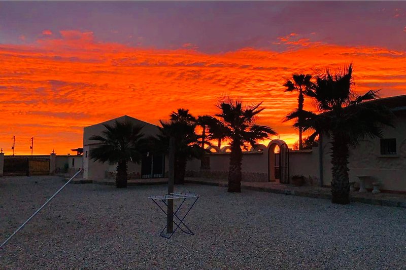 Schönes Ferienhaus mit tropischem Sonnenuntergang und rotem Himmel.
