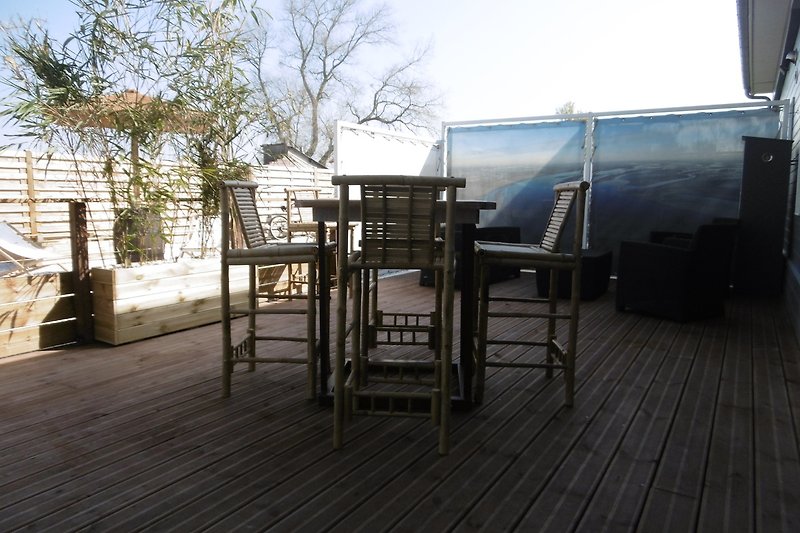 Une terrasse en bois avec des meubles et une table en plein air.