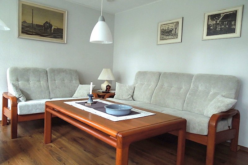 Gemütliches Wohnzimmer der www.ferienwohnung-in-schleswig.de mit Holzmöbeln, bequemer Couch und stilvoller Beleuchtung.
