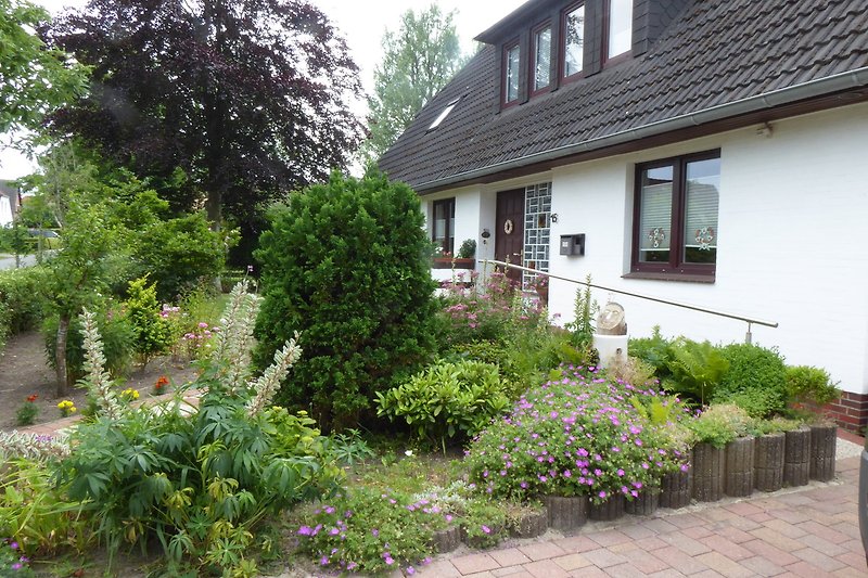 Schönes Haus mit blühenden Pflanzen und grünem Rasen.