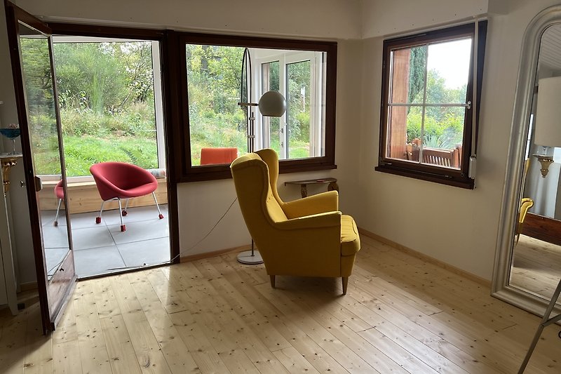 Gemütliches Wohnzimmer mit Holzboden und bequemen Sesseln.
