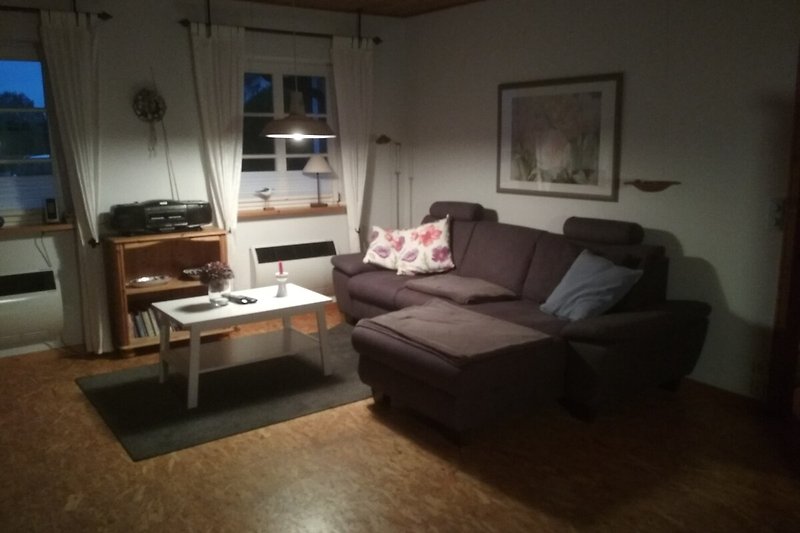 Gemütliches Wohnzimmer mit bequemer Couch, Holzmöbeln und stilvollem Lampenlicht.
