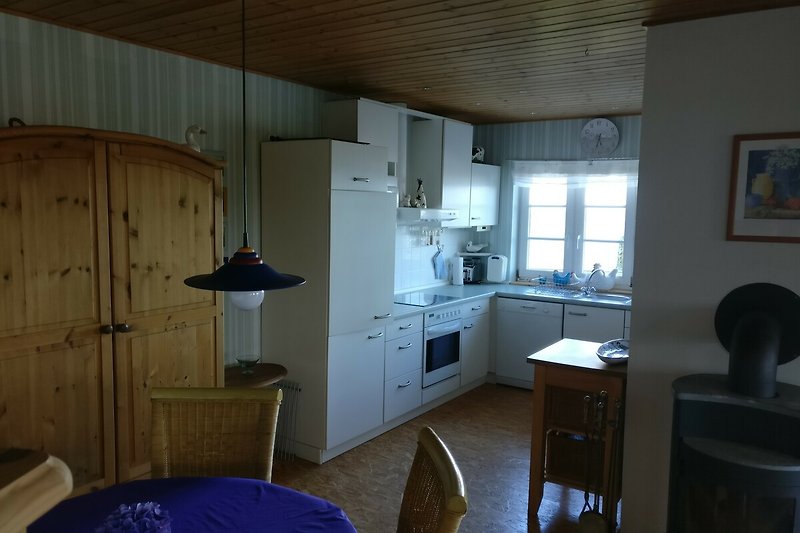 Gemütliche Küche mit Holzmöbeln, modernen Geräten und Fenstern.
