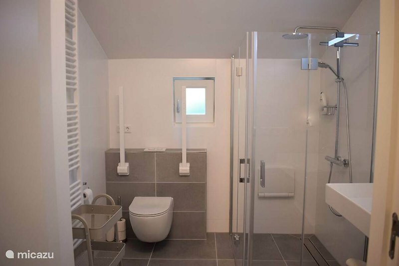 Moderne Badezimmerausstattung mit lila Duschkopf und Glasduschtür.