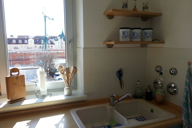 Helle Küche mit Fenster, sowie Spülbecken, Geschirrspüler und Microwelle