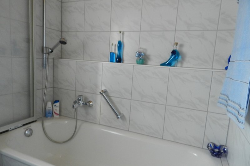 Badezimmer in der oberen Etage mit Badewanne inkl. Dusche und Spritzschutzklappwand.
