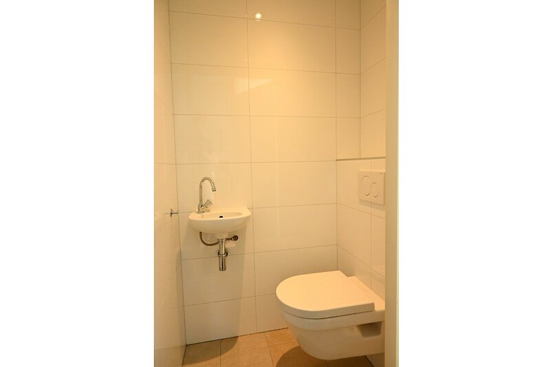 Prachtige badkamer met paarse accenten, houten vloer en keramische wastafel.