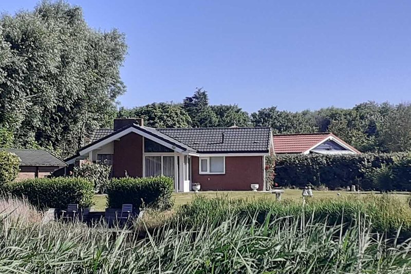 Een landelijk huis met een groene tuin en een blauwe lucht.