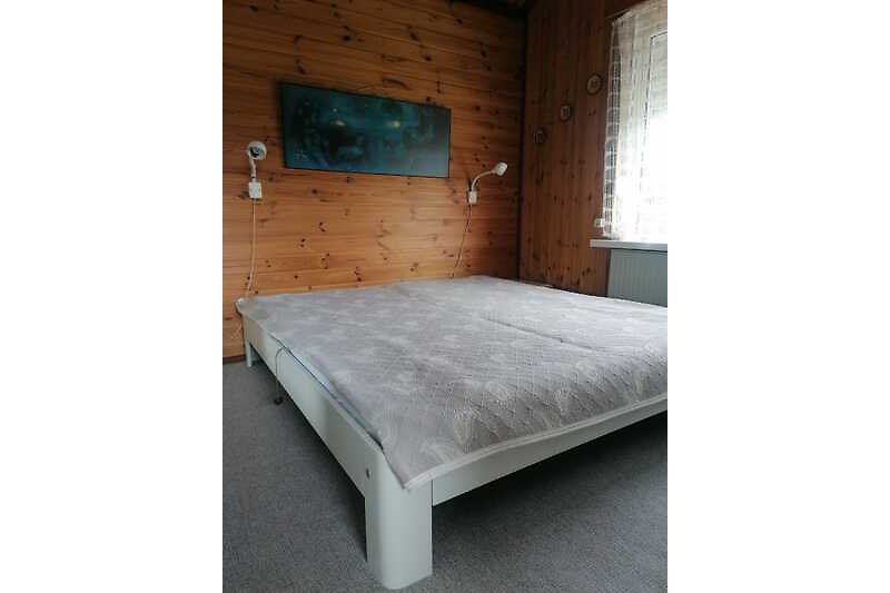 Een comfortabele slaapkamer met een houten bedframe en gordijnen.