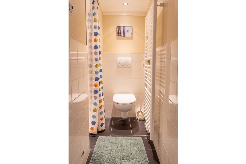 Mooie badkamer met paarse accenten en houten vloer.