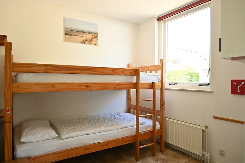 Comfortabele slaapkamer met stapelbed en houten meubels.