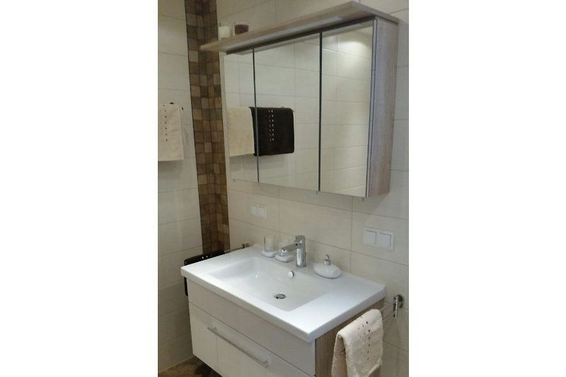 Schönes Badezimmer mit Spiegel, Waschbecken und Schrank.