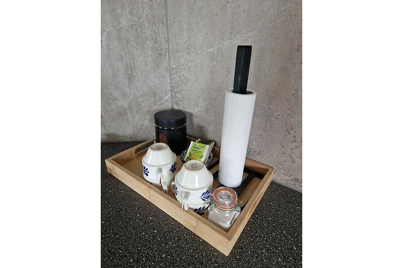 Holztisch mit Glasflasche, Tasse und Pflanze. Gemütliche Atmosphäre.