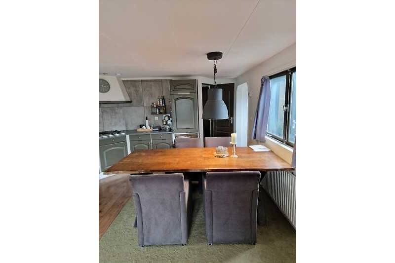 Een compleet ingerichte keuken met magnetron en oven. Er staat een grote houten tafel met 4 fijne stoelen.