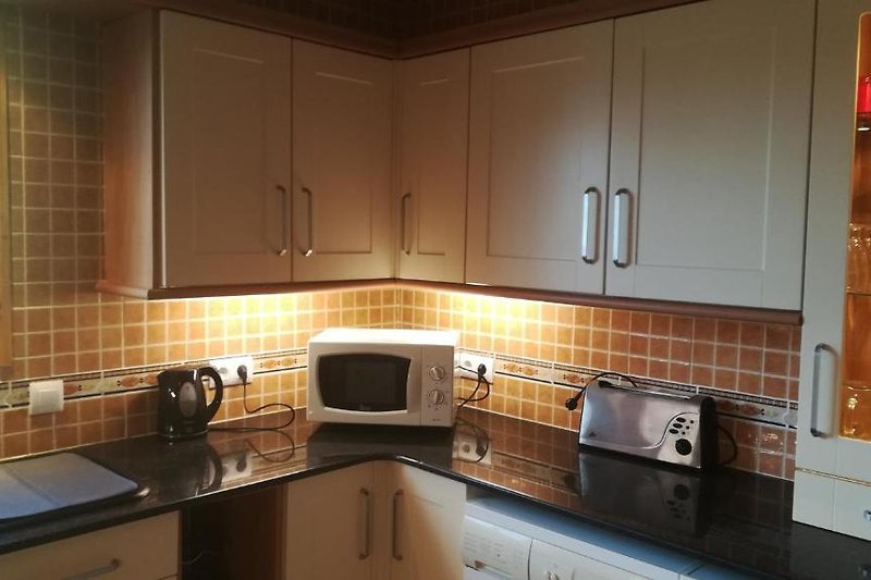Schöne Küche mit braunen Schränken, Holzboden und Granitarbeitsplatte.