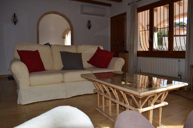 Gemütliches Wohnzimmer mit brauner Couch, Holztisch und Fenster.