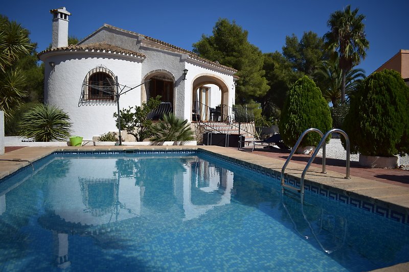 Schönes Haus mit Pool, Palmen und blauem Himmel.