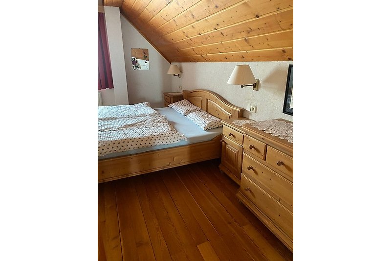 Schlafzimmer mit stilvoller Holzeinrichtung und bequemem Bett.