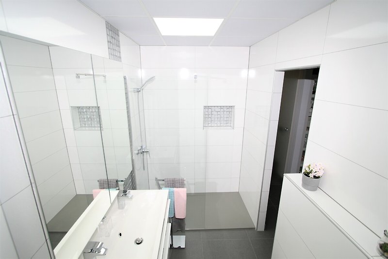 Modernes Badezimmer mit stilvoller Einrichtung, Fliesen und Dusche.