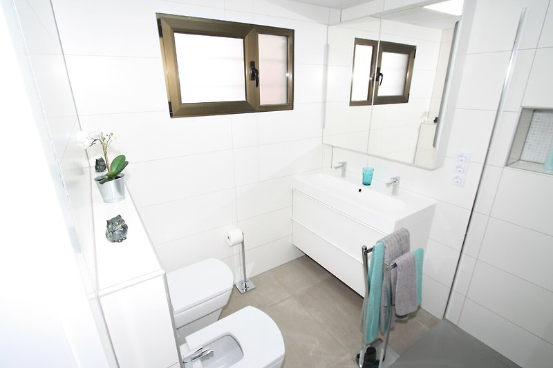Modernes Badezimmer mit modernen Akzenten, Spiegel und Waschbecken.