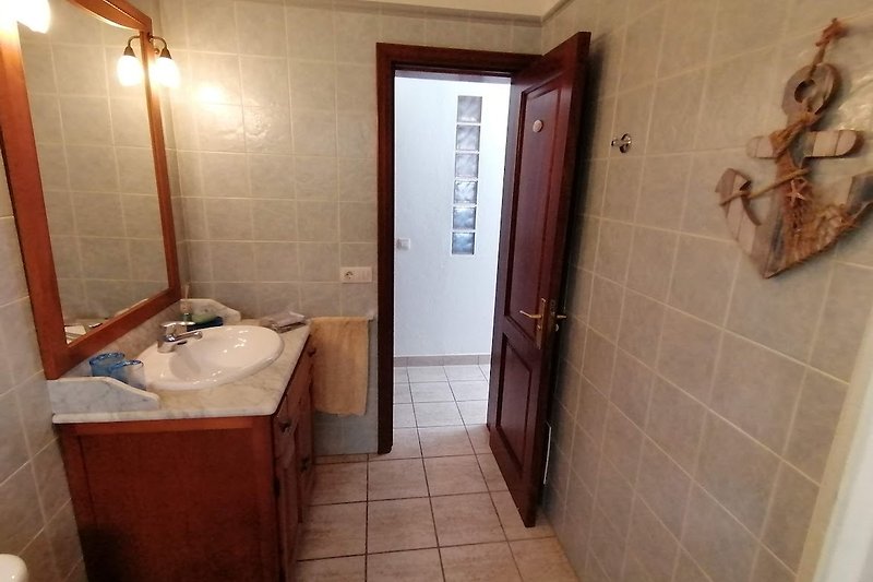 Gemütliches Badezimmer mit Spiegel, Waschbecken und Armatur.