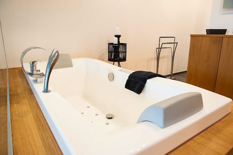 Ein stilvolles Badezimmer mit Holzfußboden und moderner Badewanne.