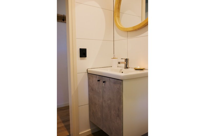 Prachtige badkamer met spiegel, kraan, wastafel en houten kasten.