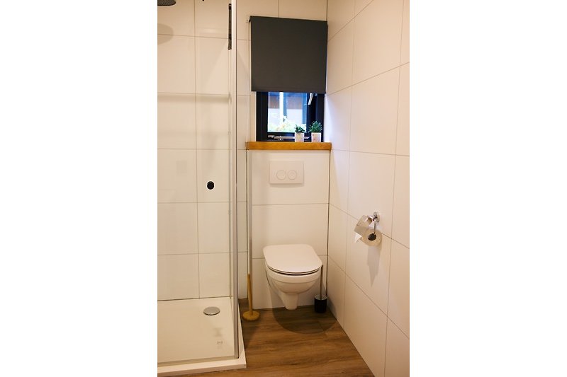 Moderne badkamer met paarse accenten, houten planken en spiegel.