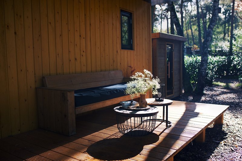 Een zonnige tuin met houten meubels en een bloempot.