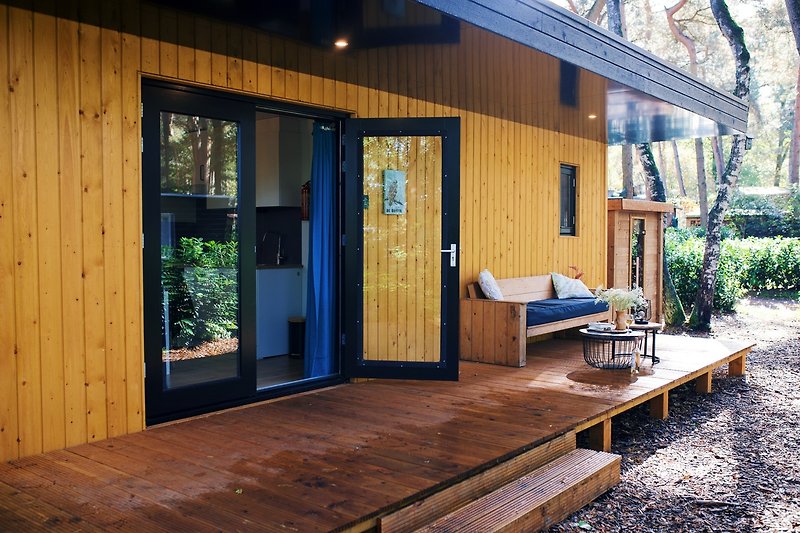 Een charmante cottage met een houten veranda en prachtige tuinmeubelen.
