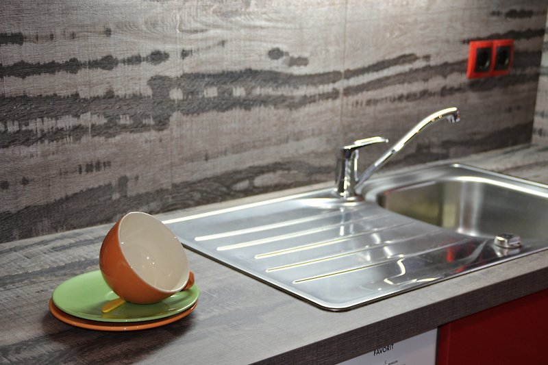 Eine moderne Küche mit Küchenspüle, Wasserhahn und Geschirr.