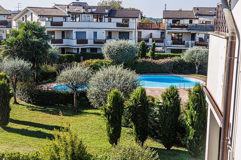 Una villa con piscina circondata da vegetazione e con una vista panoramica sulla città.