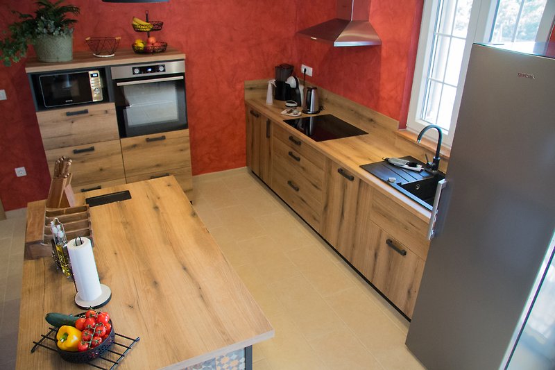 Moderne Küche mit Holzschränken, Arbeitsplatte und stilvoller Beleuchtung.
