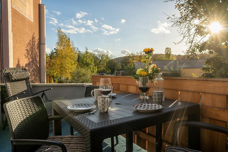 Schöne Terrasse mit Tisch, Stühlen und Blumen.