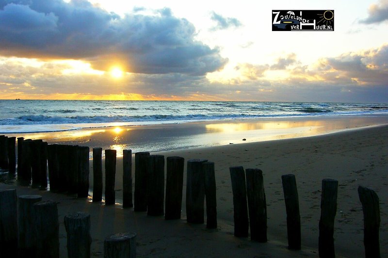 Schöner Strand mit ruhigem Meer, goldenem Sand und atemberaubendem Sonnenuntergang.