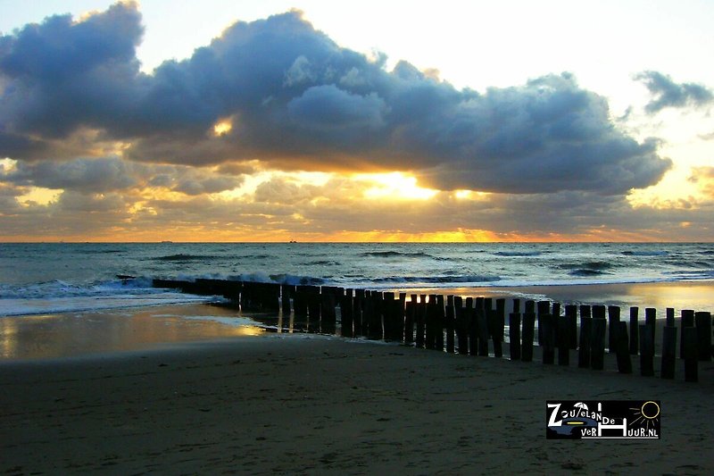 Wunderschöne Küste mit ruhigem Meer, goldenem Sand und atemberaubendem Sonnenuntergang.