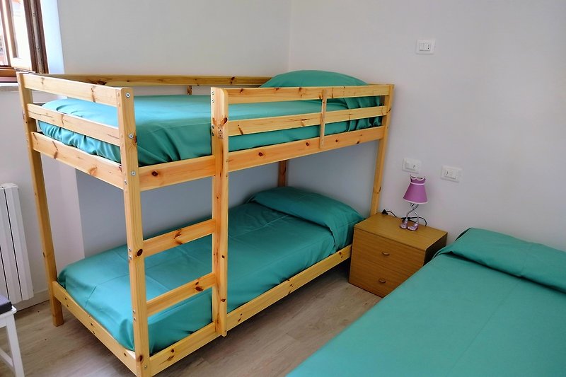 Gemütliches Schlafzimmer mit Etagenbett, Holzmöbeln und blauer Farbgebung. Komfort und Stil.