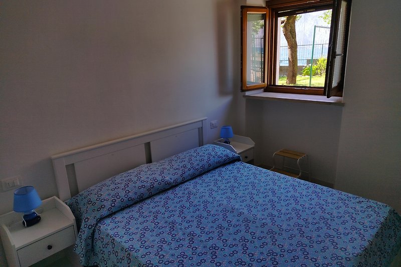Gemütliches Schlafzimmer mit Holzboden und blauem Bett. Komfort und Stil.