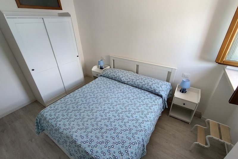 Gemütliches Schlafzimmer mit Holzmöbeln und blauem Bett. Komfort und Stil.