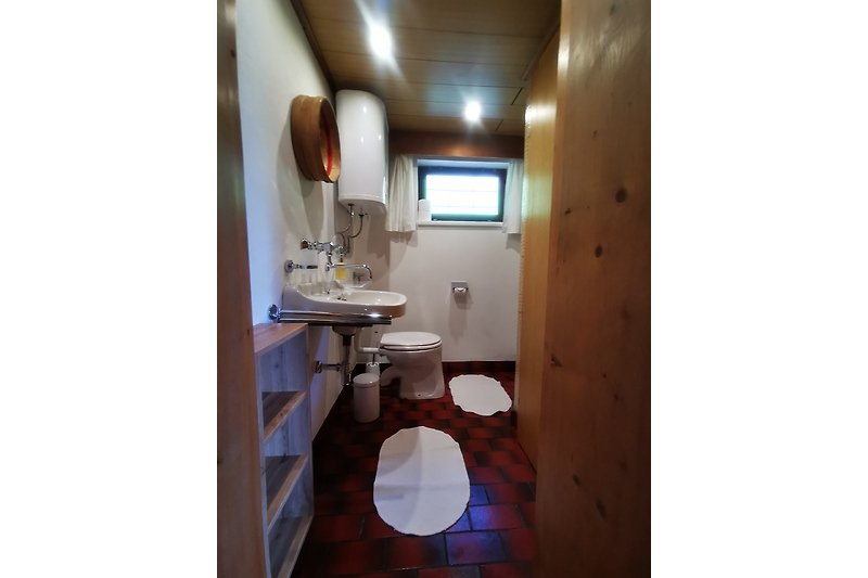 Spiegel, Waschbecken und Toilette in einem modernen Badezimmer.
