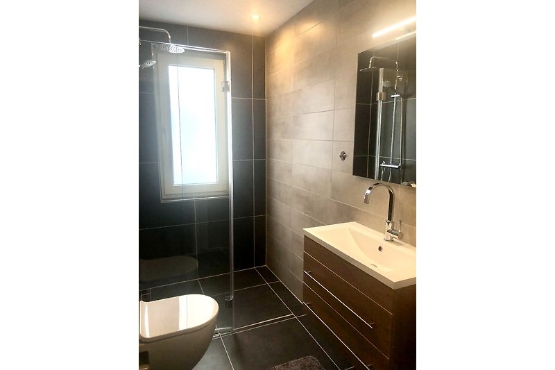 Prachtige badkamer met moderne wastafel, kraan en spiegel.