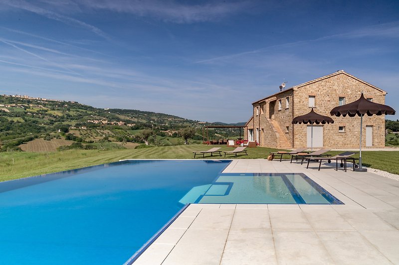 A stunning villa with a swimming pool, azure sky, and outdoor furniture.