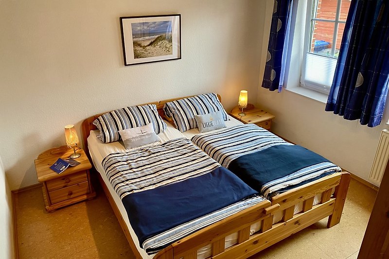 Gemütliches Schlafzimmer mit Holzbett und blauer Bettwäsche.