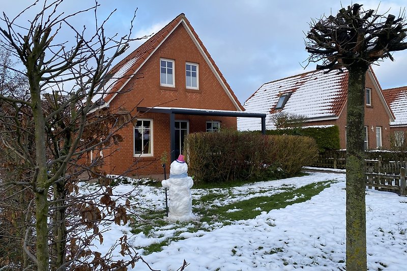 Winterliches Ferienhaus mit verschneitem Dach und gemütlichem Kamin.