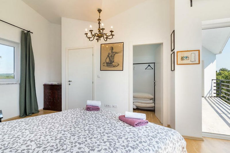 Schlafraum 3: Blick ins Schlafzimmer mit begehbarem Kleiderschrank und Zugang zur Terrasse.
