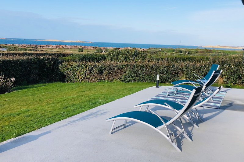Schöne Terrasse mit Gartenmöbeln und Blick auf das Meer.