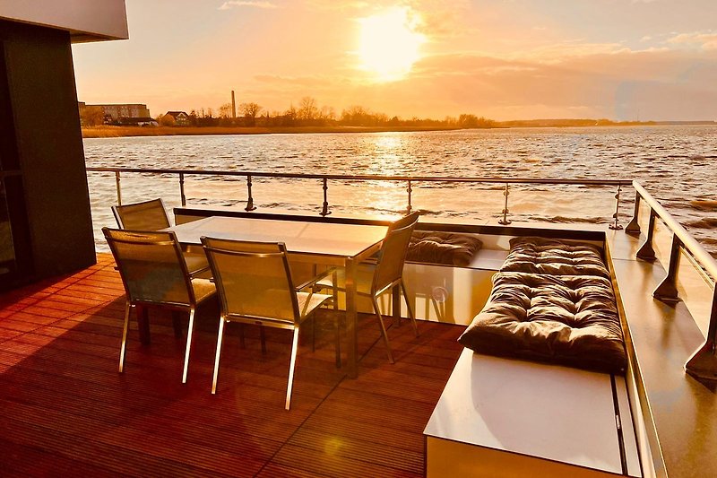 Genießen Sie den Sonnenuntergang am Seeufer mit stilvollen Möbeln und atemberaubender Aussicht.